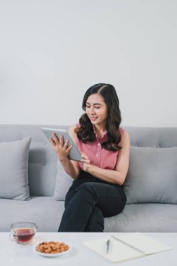 Online alışveriş, fashioanble beyaz kıyafetiyle, çok güzel ışık tasarım iç kapalı çok rahat evde kanepede Asya kadının işi