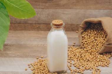 şişe soya süt ve soya fasulyesi ahşap arka plan üzerinde