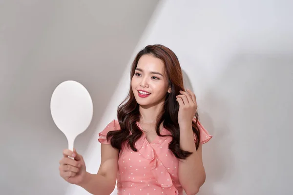 Happy young woman looking on mirror