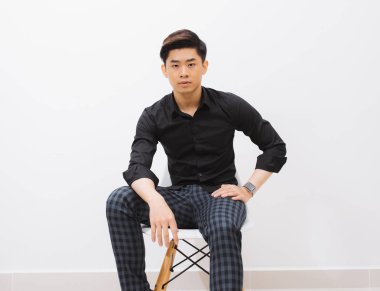 Raslantı yakışıklı. Stüdyo çekim yakışıklı genç adam sandalyede oturan ve fotoğraf makinesi ile bakarak gülümsemek