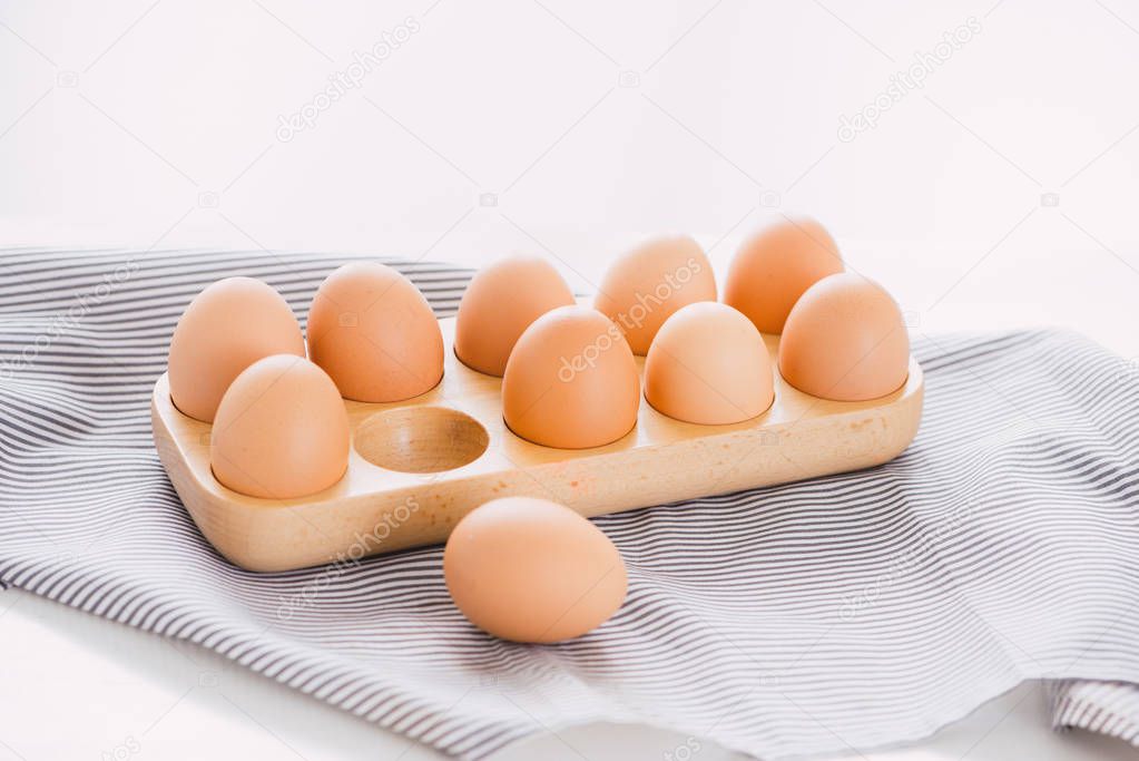 Close-up view of raw chicken eggs in egg box on white background