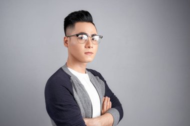 Casual adam elleriyle gülümseyen ayakta gri studio duvara geçti