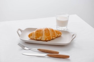 Kahvaltıda taze pişmiş kruvasan ve bir bardak soya sütü.