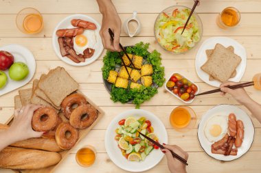 Arkadaşlarınızla akşam yemeği zevk. Grup birlikte ahşap masada otururken yemeğe insan Üstten Görünüm