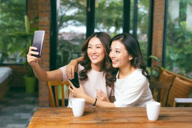 İki genç çekici kadın selfie kafede masada oturan alarak.