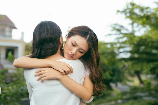 Sad unhappy young women hugging standing outdoors