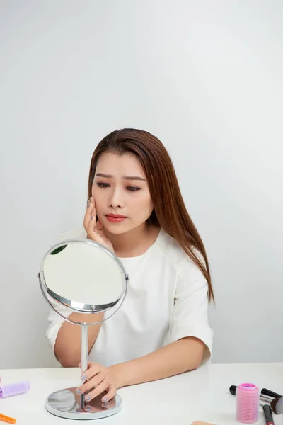 Young asian woman looking a mirror.