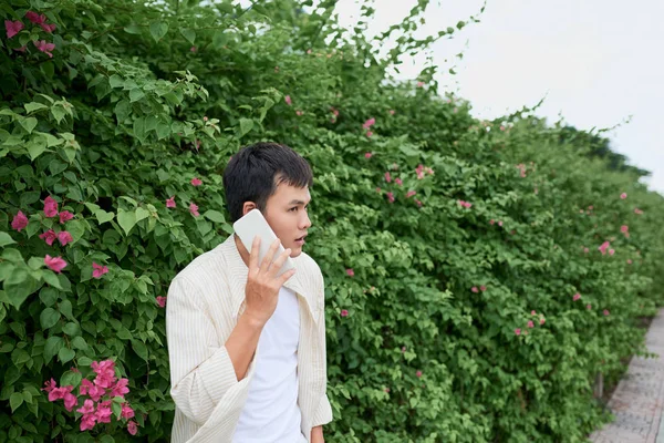 英俊的年轻人讲电话在绿色夏天公园散步 — 图库照片