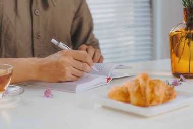 Beyaz ahşap masa ve çay Not defteri ile çalışırken oturan bir adamın kırpılmış görüntü