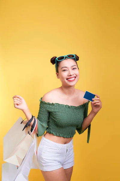 购物亚洲妇女持有购物袋和一张黄色背景的信用卡 — 图库照片