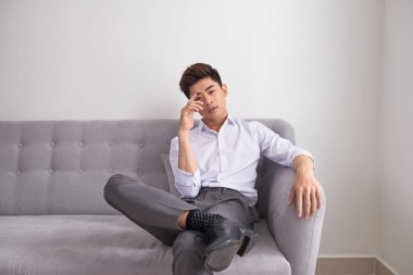 Mutlu yakışıklı Asya adam evde oturma odasında kanepede rahatlatıcı