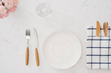 Beyaz tabak çatal ve bıçak masada, üstten görünüm 
