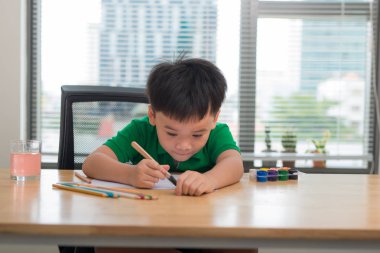 Sevimli gülümseyen Asyalı çocuk eğitim kavramı masa başında otururken ödev 