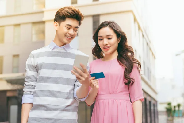 Beautiful asian couple walking with credit card in city, shopping concept