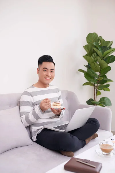 Hombre Feliz Trabajando Con Ordenador Portátil Comer Pastel Sofá — Foto de Stock