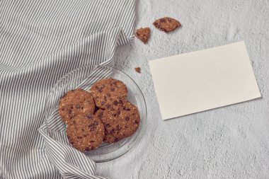 Kase ve boş ileti kartı beyaz taş zemin üzerine çikolatalı kurabiye