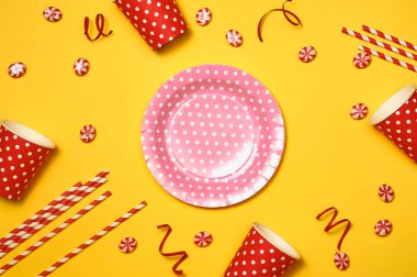 Parlak gökkuşağı lolipop şekerler desenli kağıt tabak, bardak ve payet renkli sarı zemin üzerine