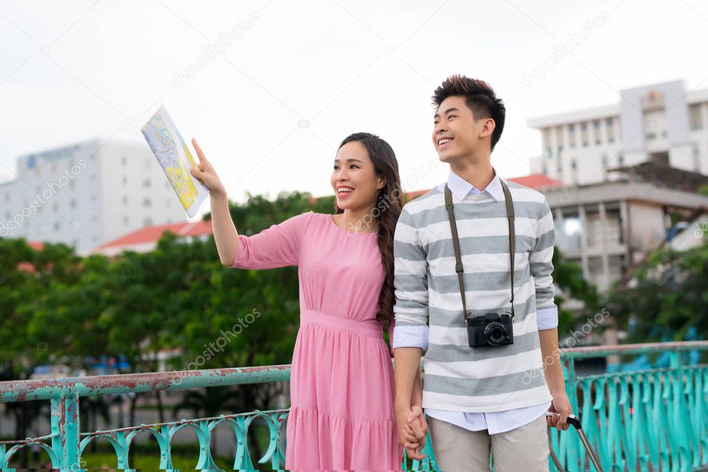 Happy young asian couple traveling in city