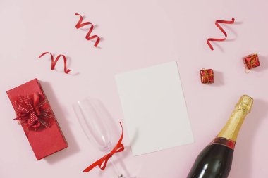 şampanya şişesi ve kurdeleler ile pembe arka plan üzerinde kırmızı hediye kutusu