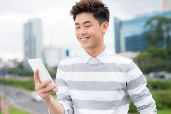 若いアジア系のビジネスマン笑顔とスマート フォンを使用して — ストック写真
