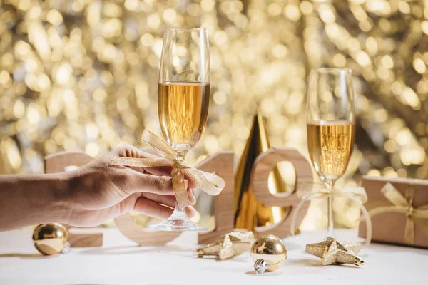 黄金キラキラ背景に新年のお祝いにシャンパン グラスを持って人間の手 — ストック写真