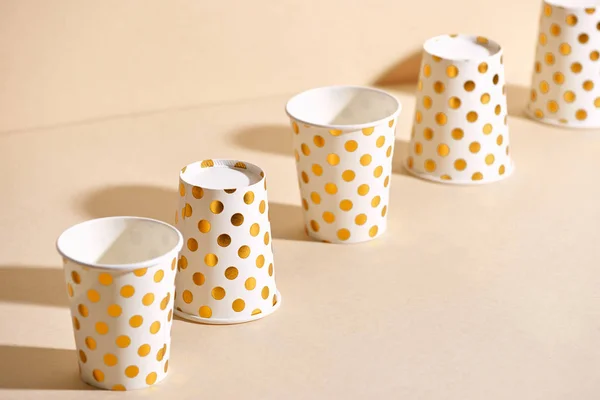 Golden polka dot paper cups isolated on beige background