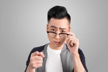 Sürpriz yakışıklı adam dokunmadan gösterilen gözlük ve gri arka plan üzerinde işaretleme