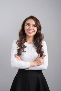 Gri arka plan üzerinde ararken gülümseyen kendine güvenen kadın portresi