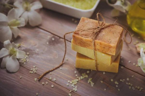 Natural handmade soap pieces and orchid on wooden surface