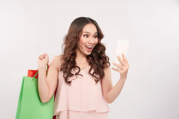 Surprised Young Woman Using Smartphone Shopping Bags White Background — Stock Photo, Image