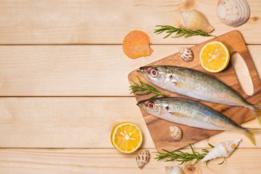 Maddeler ile pişirme balık yemek. Limon dilimleri ve ahşap masa üzerinde otlar ile dekore edilmiş taze çiğ balık.