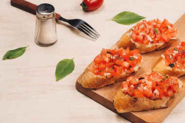 Kızarmış domatesli İtalyan bruschetta, mozzarella peyniri ve kesim tahtasında otlar.