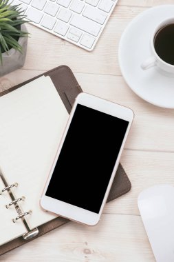 Kahve fincanı, smartphone ve ahşap masa üstünde defter ile çalışma alanı