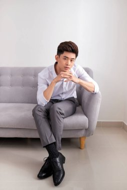 kanepede oturan ve beyaz arka plan üzerinde kameraya bakarak işadamı