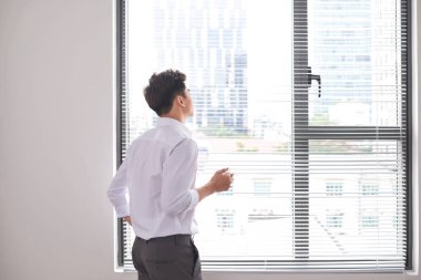 Bir fincan kahve duran ofis pencere tutarak kendine güvenen genç işadamı portresi