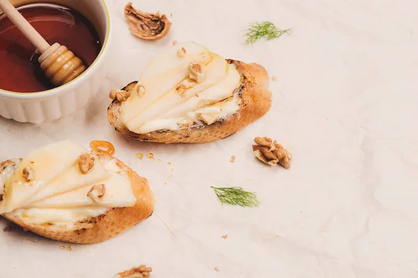 Appetizer bruschetta with apple, honey and walnuts on white surface