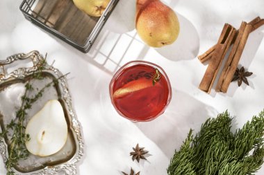 baharatlı sıcak kırmızı şarap mulled tarçın, Yıldız anason ve dilim armut cam malzemelerle beyaz masada