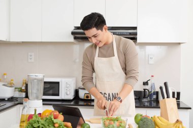 Tablet bilgisayar kullanan adam evde mutfak, yemek.