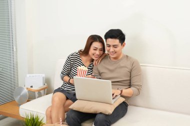 Genç çift laptop ile internette sörf. Modern beyaz daire arka planda