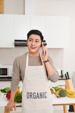 Cep telefonundan konuşuyor ve yemek yemek mutfakta yakışıklı genç İspanyol adam