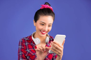 Mutlu Genç Asyalı kadın smartphone üzerinde mavi arka plan kullanarak