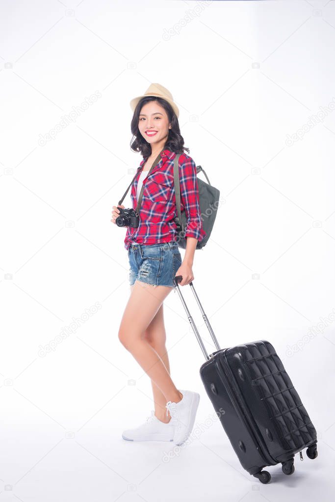 Young asian female traveler standing with suitcase and camera on white background