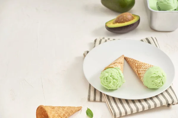 Green avocado ice cream in waffle cones on white background