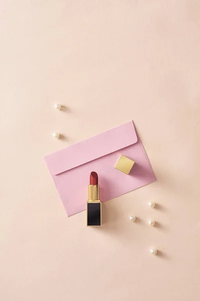 Lippenstift Auf Rosa Umschlag Mit Perlen Auf Pastellfarbenem Hintergrund — Stockfoto
