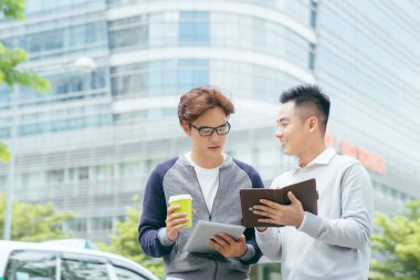 Tablet bilgisayarı kullanmak ve arka plan üzerinde ofis ile yürüme iki gülümseyen iş adamları