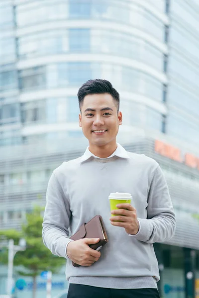市の手でコーヒーを飲みながら立っている青年実業家 — ストック写真
