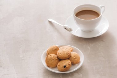 Kremalı kahve kurabiyeleri ve beyaz arka plan üzerinde kırpma yolu izole Paslanmaz çay kaşığı beyaz fincan