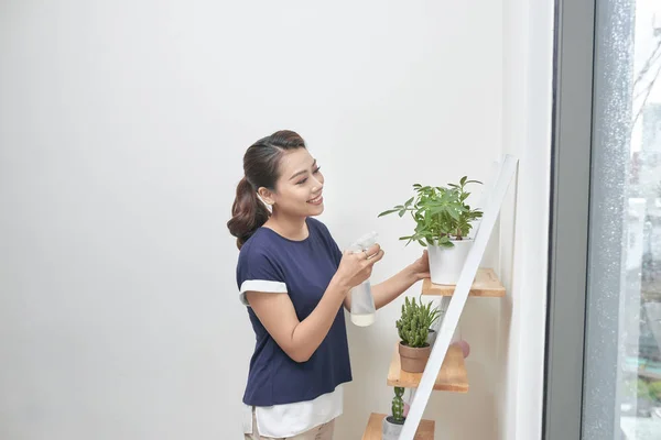 若い魅力的なアジア女性自宅植物に吹きかける — ストック写真