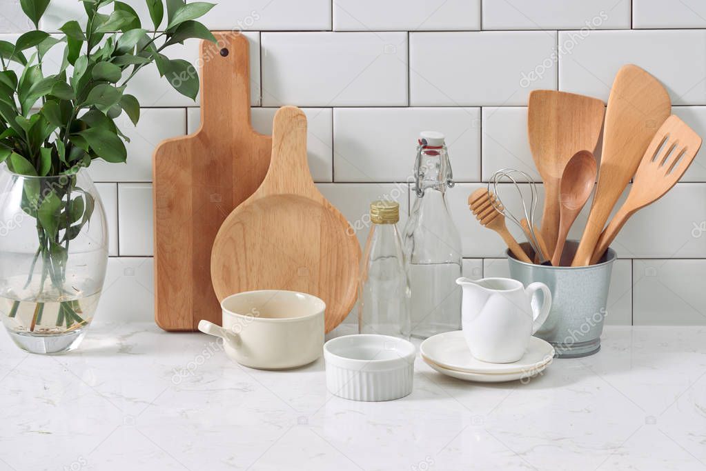 rustic kitchenware and ceramic jug with wooden cooking utensil set on white tile background
