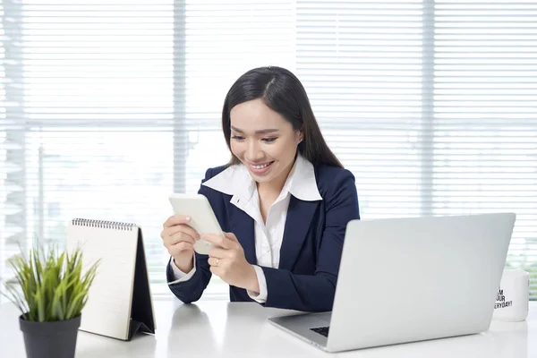 Asian Kobieta Siedzi Przy Biurku Laptopa Przy Użyciu Telefonu Komórkowego — Zdjęcie stockowe